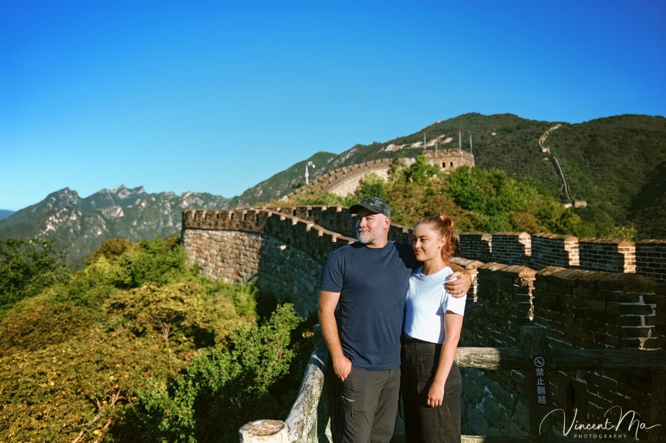 An American couple posing for romantic pictures against the backdrop of Mutianyu Great Wall in Beijing, China. The Great Wall winds through the mountains, and the couple shows their love in the photos