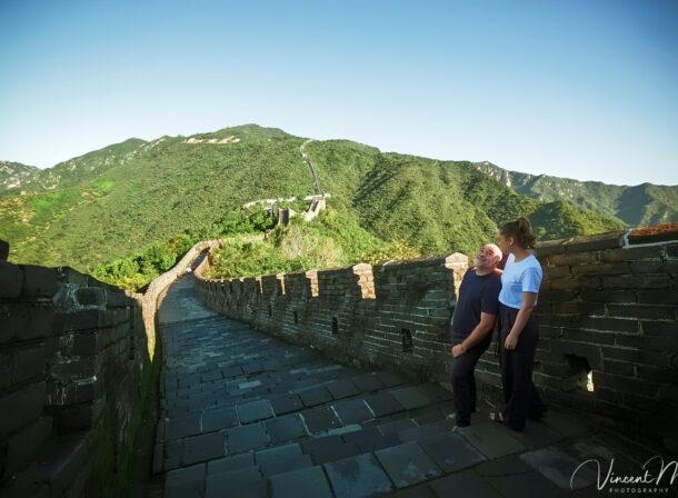 An American couple posing for romantic pictures against the backdrop of Mutianyu Great Wall in Beijing, China. The Great Wall winds through the mountains, and the couple shows their love in the photos