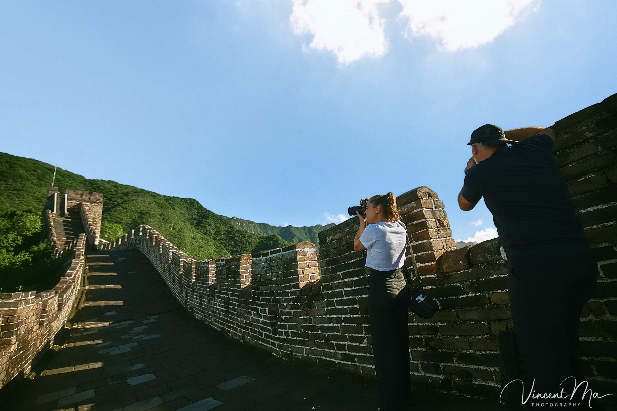 An American couple posing for romantic pictures against the backdrop of Mutianyu Great Wall in Beijing, China. The Great Wall winds through the mountains, and the couple shows their love in the photos
