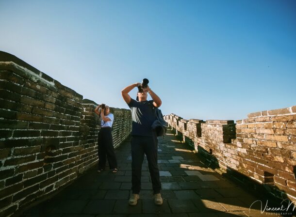 An American couple posing for romantic pictures against the backdrop of Mutianyu Great Wall in Beijing, China. The Great Wall winds through the mountains, and the couple shows their love in the photos