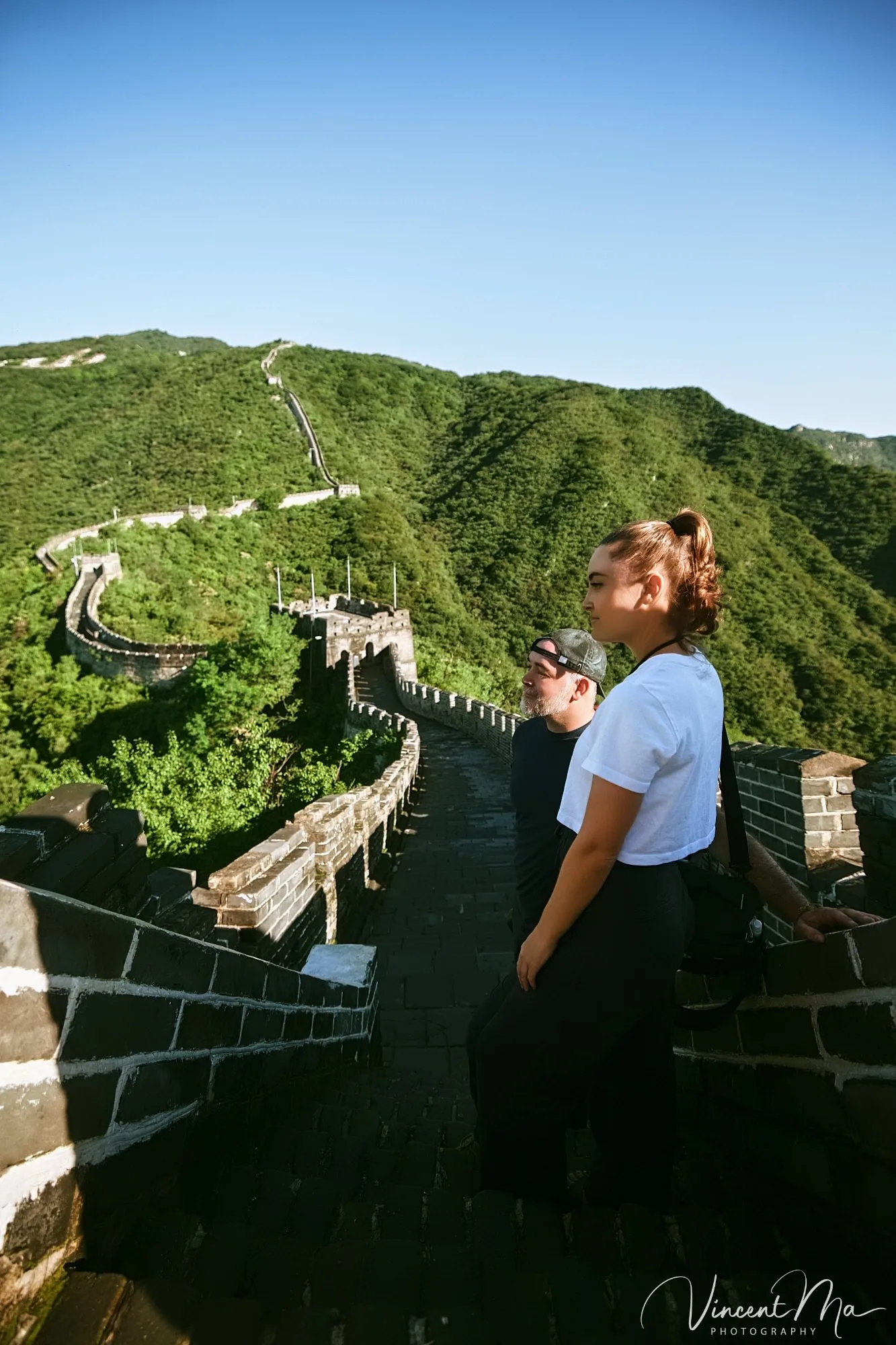 An American couple posing for romantic pictures against the backdrop of Mutianyu Great Wall in Beijing, China. The Great Wall winds through the mountains, and the couple shows their love in the photos.Beijing photoshoot-Beijing photographer