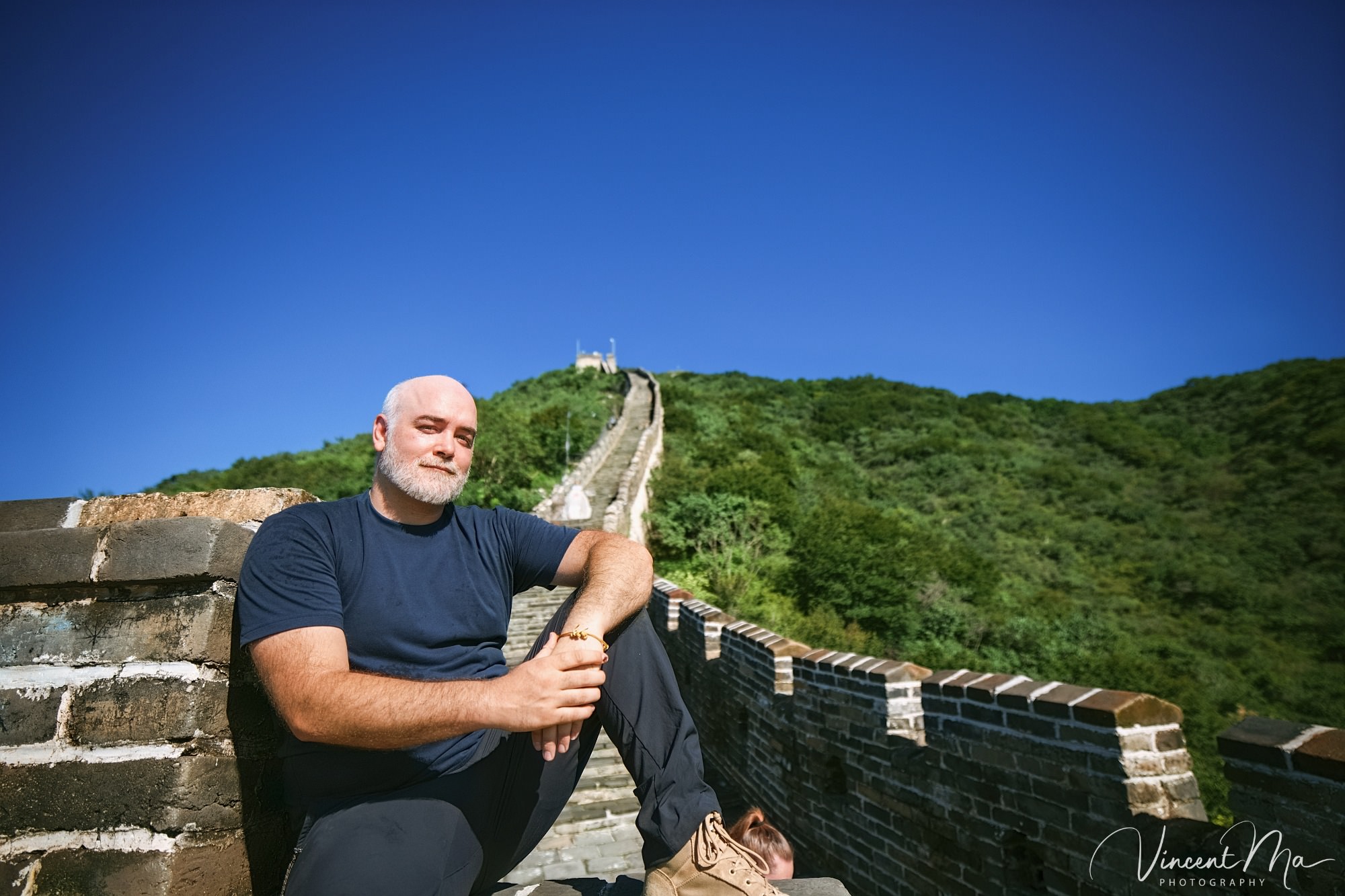 An American couple posing for romantic pictures against the backdrop of Mutianyu Great Wall in Beijing, China. The Great Wall winds through the mountains, and the couple shows their love in the photos