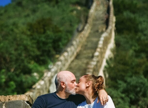 An American couple posing for romantic pictures against the backdrop of Mutianyu Great Wall in Beijing, China. The Great Wall winds through the mountains, and the couple shows their love in the photos
