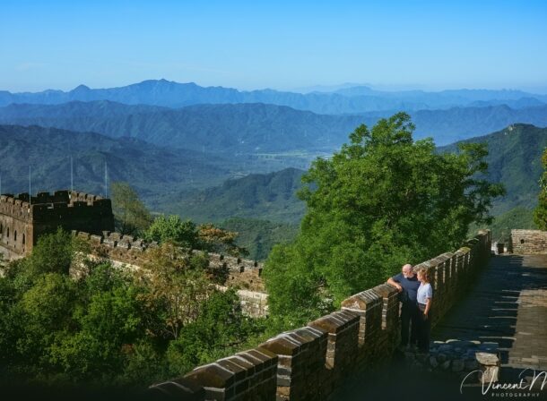 An American couple posing for romantic pictures against the backdrop of Mutianyu Great Wall in Beijing, China. The Great Wall winds through the mountains, and the couple shows their love in the photos