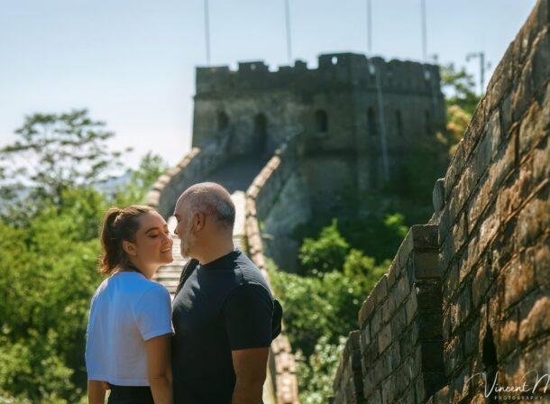 An American couple posing for romantic pictures against the backdrop of Mutianyu Great Wall in Beijing, China. The Great Wall winds through the mountains, and the couple shows their love in the photos