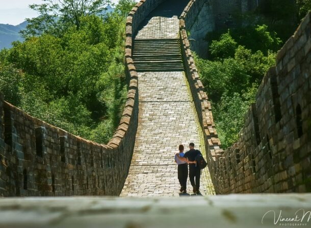 An American couple posing for romantic pictures against the backdrop of Mutianyu Great Wall in Beijing, China. The Great Wall winds through the mountains, and the couple shows their love in the photos