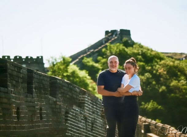 An American couple posing for romantic pictures against the backdrop of Mutianyu Great Wall in Beijing, China. The Great Wall winds through the mountains, and the couple shows their love in the photos