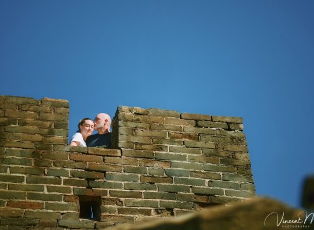 An American couple posing for romantic pictures against the backdrop of Mutianyu Great Wall in Beijing, China. The Great Wall winds through the mountains, and the couple shows their love in the photos