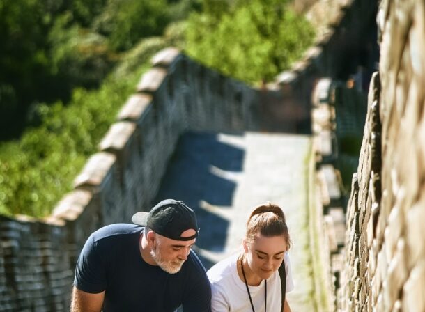 An American couple posing for romantic pictures against the backdrop of Mutianyu Great Wall in Beijing, China. The Great Wall winds through the mountains, and the couple shows their love in the photos