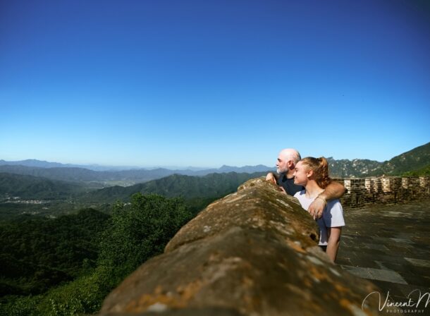 An American couple posing for romantic pictures against the backdrop of Mutianyu Great Wall in Beijing, China. The Great Wall winds through the mountains, and the couple shows their love in the photos