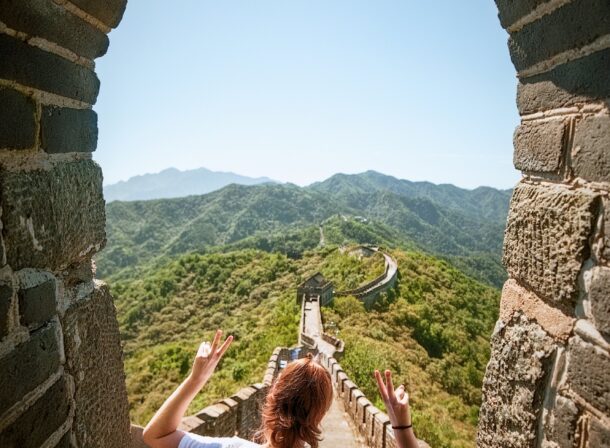 An American couple posing for romantic pictures against the backdrop of Mutianyu Great Wall in Beijing, China. The Great Wall winds through the mountains, and the couple shows their love in the photos