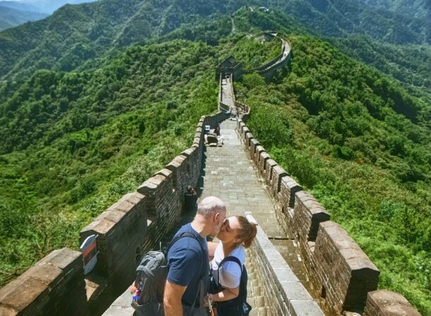 An American couple posing for romantic pictures against the backdrop of Mutianyu Great Wall in Beijing, China. The Great Wall winds through the mountains, and the couple shows their love in the photos