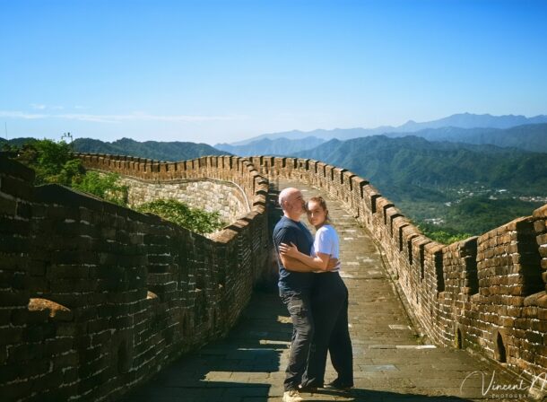 An American couple posing for romantic pictures against the backdrop of Mutianyu Great Wall in Beijing, China. The Great Wall winds through the mountains, and the couple shows their love in the photos