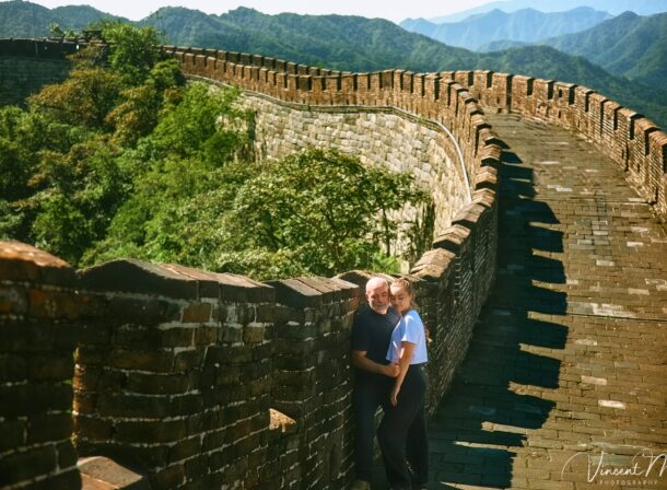 An American couple posing for romantic pictures against the backdrop of Mutianyu Great Wall in Beijing, China. The Great Wall winds through the mountains, and the couple shows their love in the photos