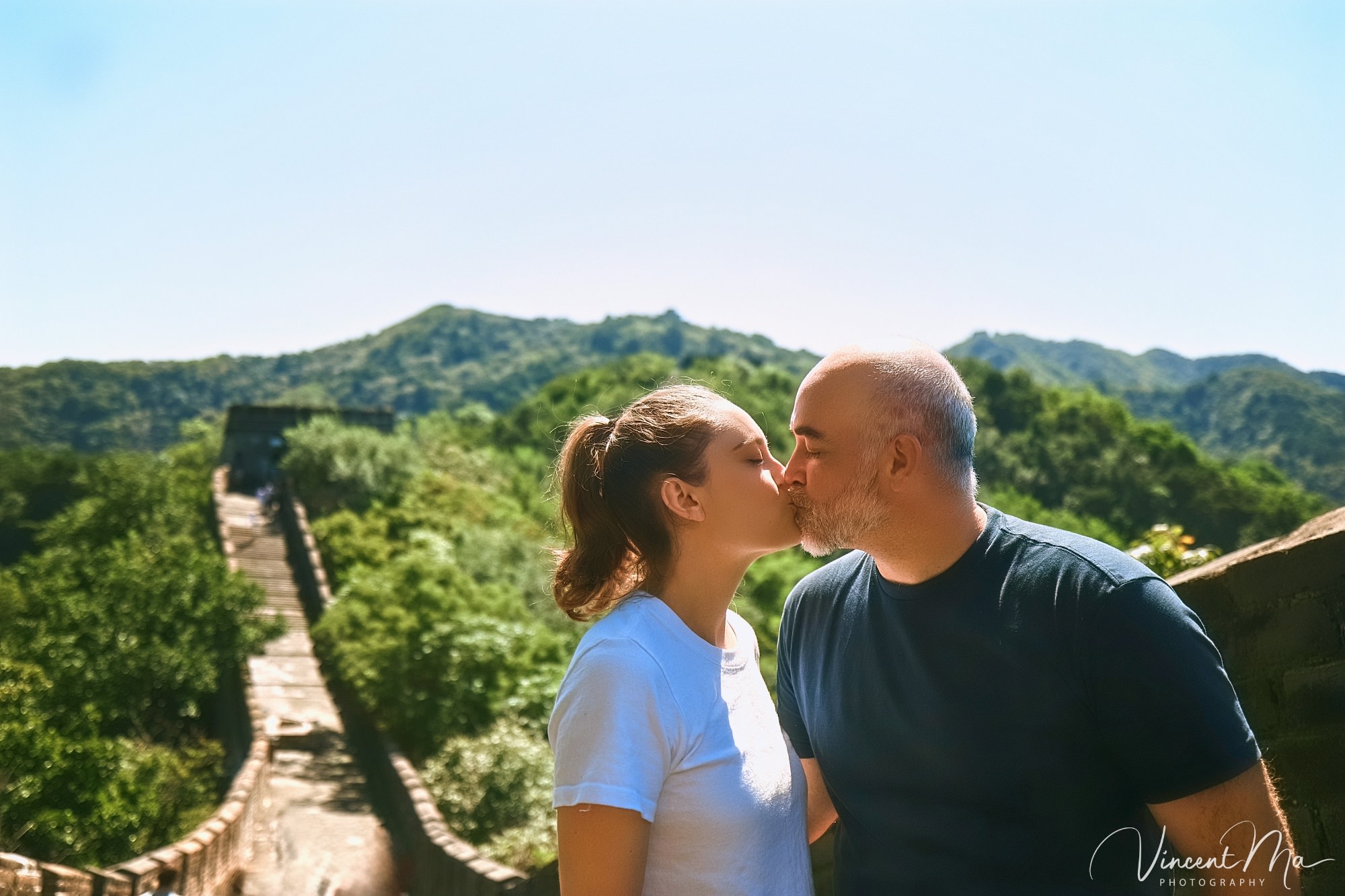 An American couple posing for romantic pictures against the backdrop of Mutianyu Great Wall in Beijing, China. The Great Wall winds through the mountains, and the couple shows their love in the photos