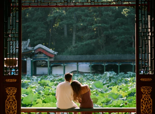 Couple enjoying a romantic moment at the Garden of Harmonious Interests in Beijing's Summer Palace, surrounded by traditional Chinese garden scenery with lakes and pavilions. Engagement shooting in summer palace.