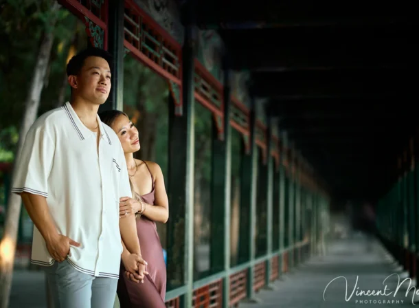 Couple enjoying a romantic moment at The Long Corridor in Beijing's Summer Palace, surrounded by traditional Chinese garden scenery with lakes and pavilions.