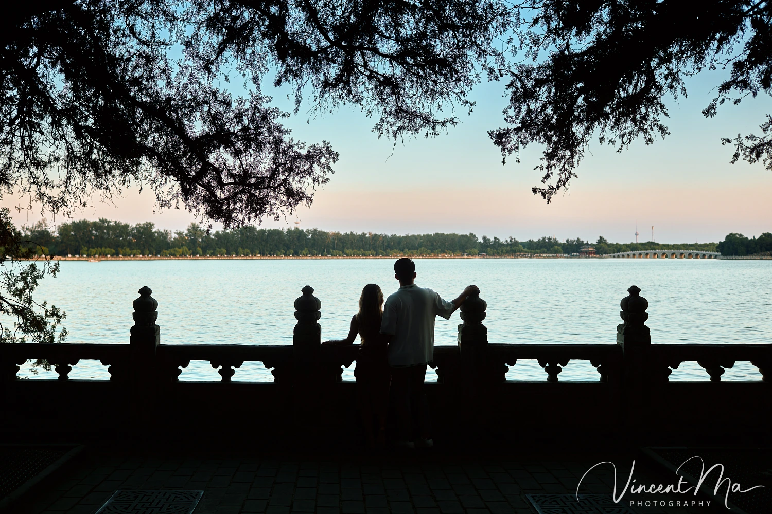 A couple shares an intimate moment with the magnificent architecture of the Summer Palace in sunset in the background.