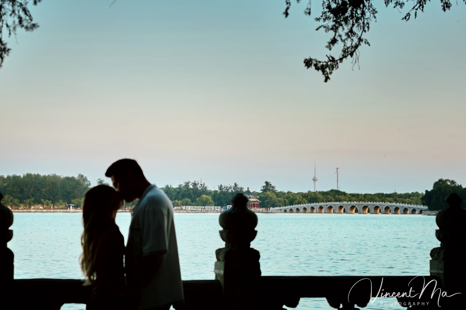 A couple shares an intimate moment with the magnificent architecture of the Summer Palace in Beijing in the background.