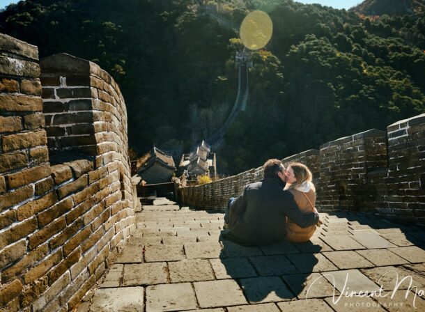 Man proposing to woman on Mutianyu Great Wall during autumn with mountains in background