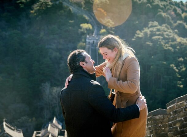 Man proposing to woman on Mutianyu Great Wall during autumn with mountains in background