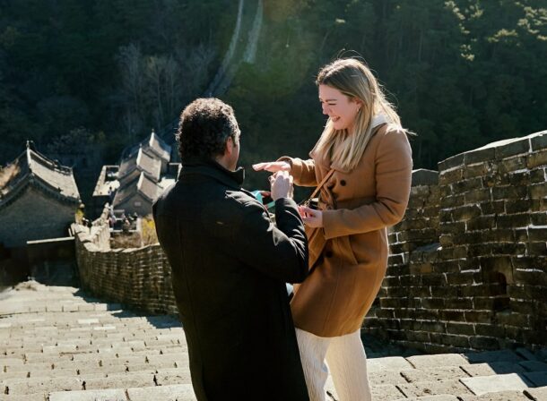 Man proposing to woman on Mutianyu Great Wall during autumn with mountains in background