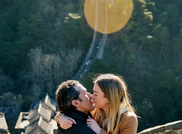 Man proposing to woman on Mutianyu Great Wall during autumn with mountains in background