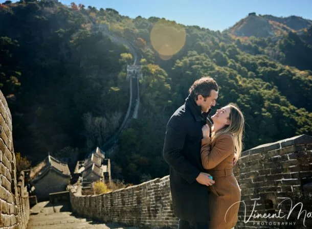 Man proposing to woman on Mutianyu Great Wall during autumn with mountains in background