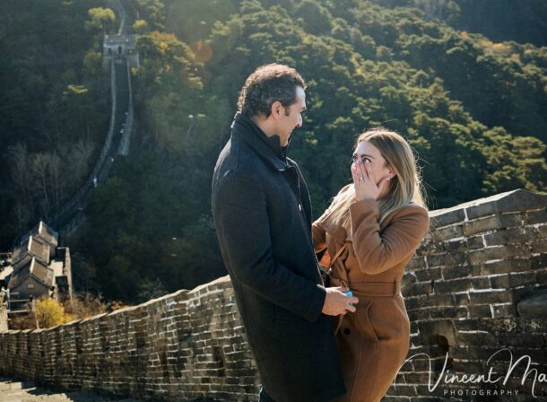 Man proposing to woman on Mutianyu Great Wall during autumn with mountains in background