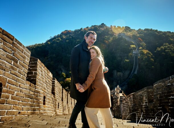Man proposing to woman on Mutianyu Great Wall during autumn with mountains in background