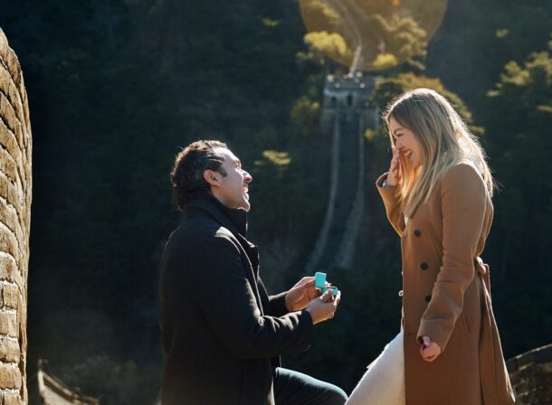 Man proposing to woman on Mutianyu Great Wall during autumn with mountains in background