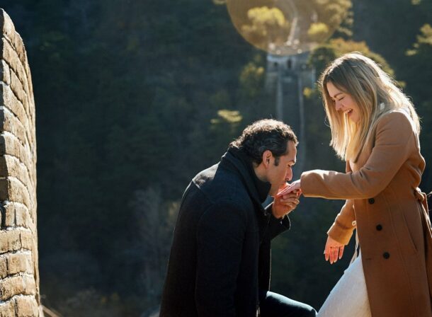 Man proposing to woman on Mutianyu Great Wall during autumn with mountains in background