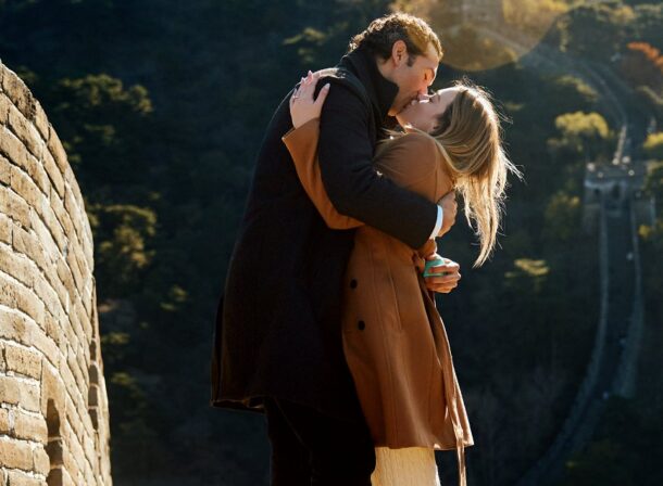 Man proposing to woman on Mutianyu Great Wall during autumn with mountains in background