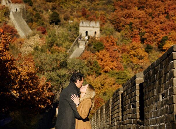 Surprise marriage proposal engagement shooting on Mutianyu Great Wall with ancient bricks and autumn leaves in background