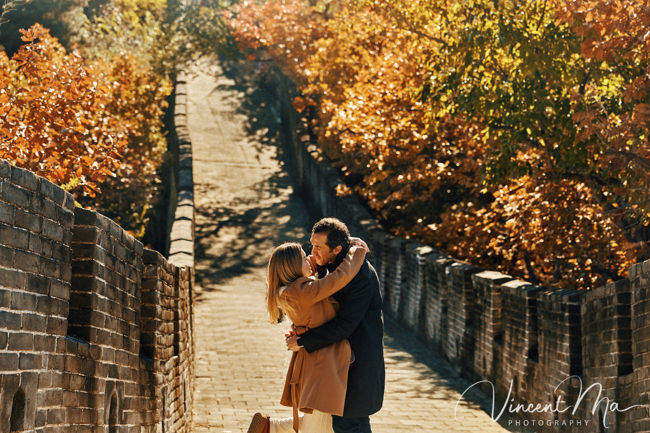 Surprise marriage proposal engagement shooting on Mutianyu Great Wall with ancient bricks and autumn leaves in background