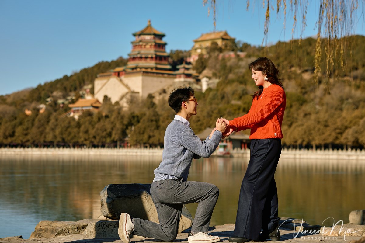 Beijing proposal.Couple sharing a romantic kiss with the Tower of Buddhist Incense in the background at the Summer Palace, Beijing. Winter engagement photography with clear blue sky
