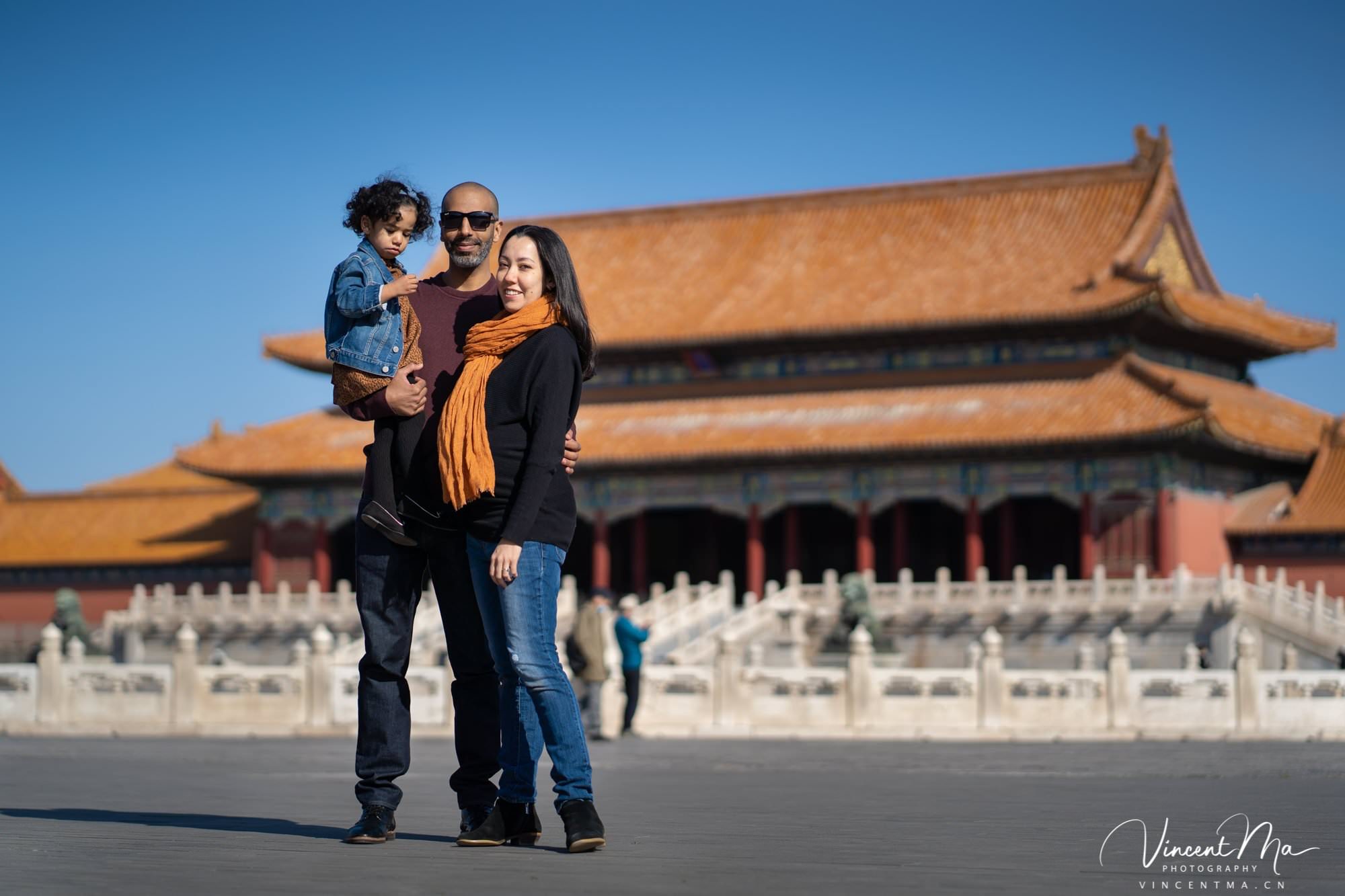 US family of three with toddler laughing in front of the Hall of Supreme Harmony at Forbidden City, blue sky and no tourists.Family photography by Vincent Ma