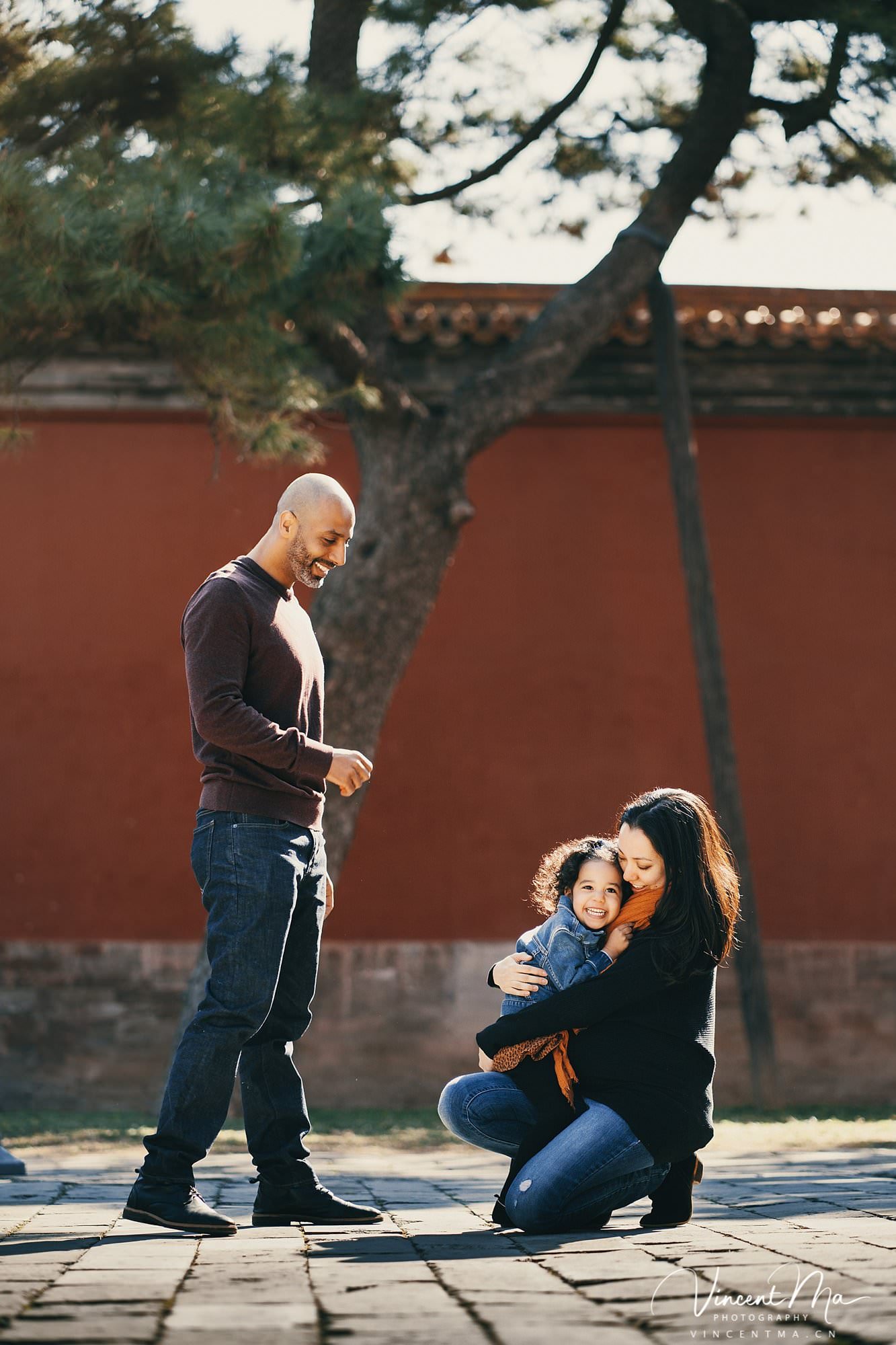 US family of three with toddler laughing in front of the Hall of Supreme Harmony at Forbidden City, blue sky and no tourists.Family photography by Vincent Ma