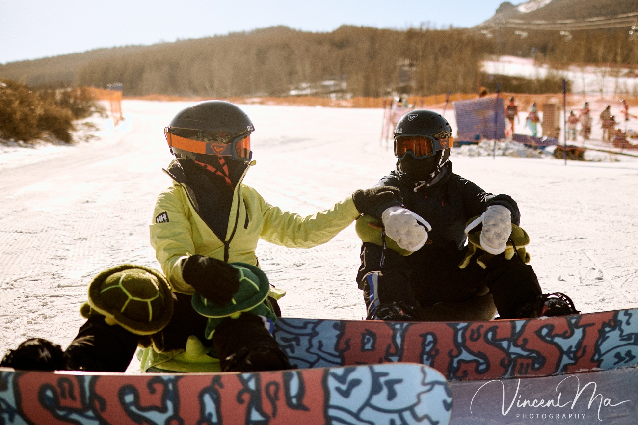 Same-sex couple Claire and April holding hands on a snowy slope in Chongli at a ski resort to celebrate their online wedding.