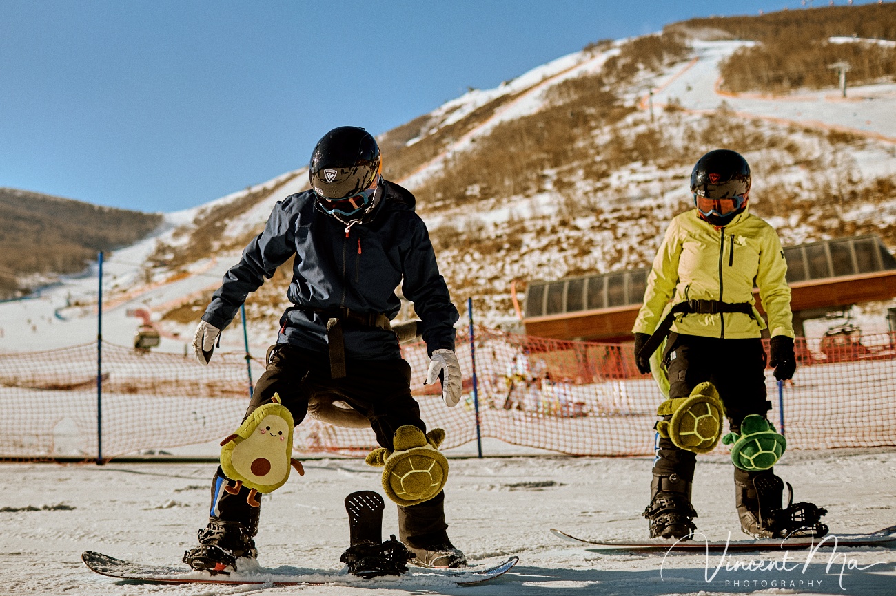 Same-sex couple Claire and April holding hands on a snowy slope in Chongli at a ski resort to celebrate their online wedding.