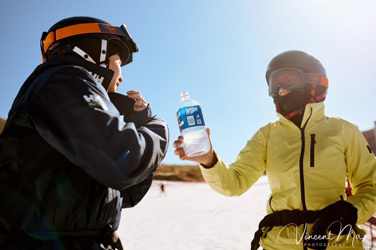 Same-sex couple Claire and April holding hands on a snowy slope in Chongli at a ski resort to celebrate their online wedding.