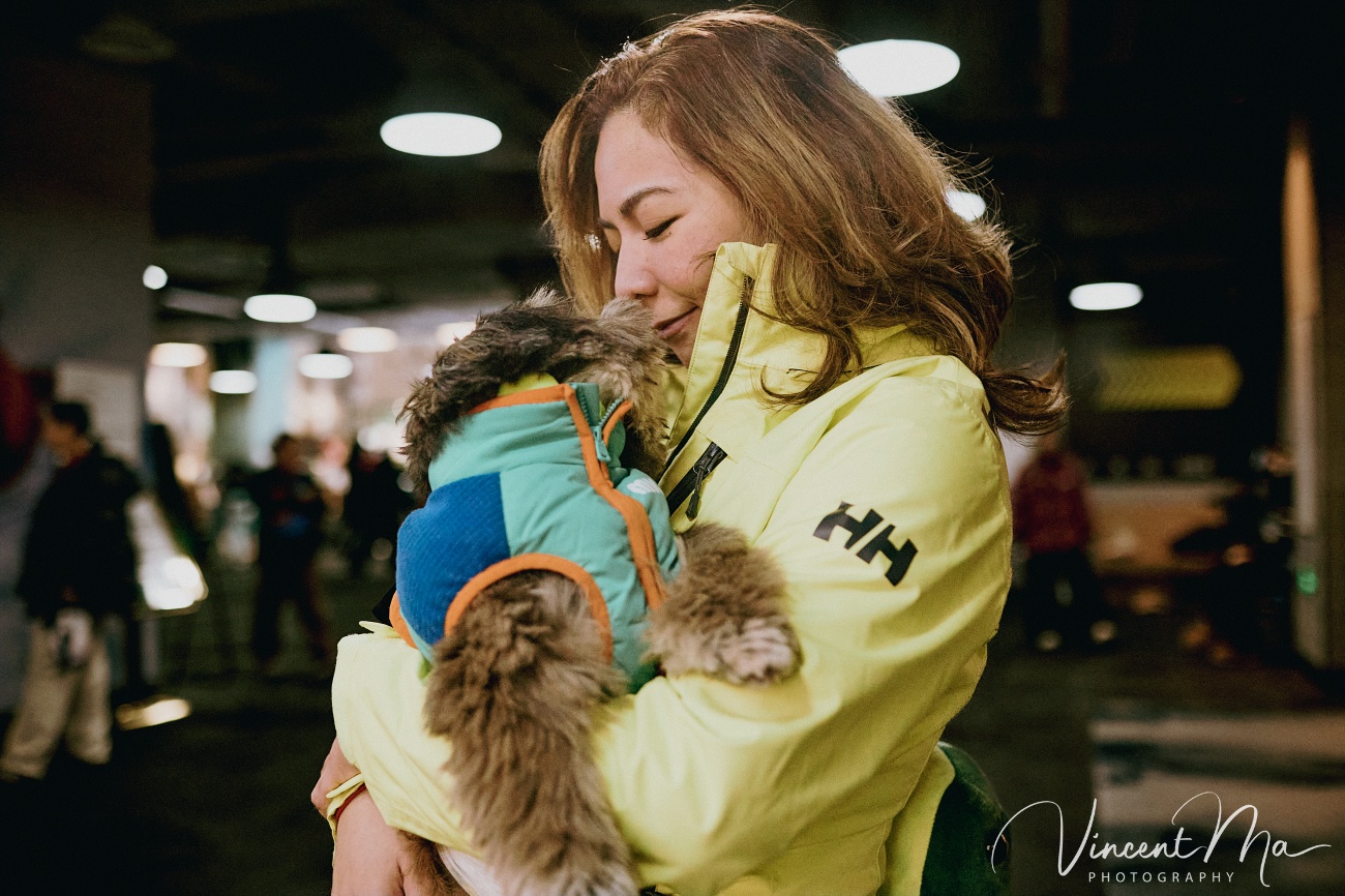Same-sex couple snowboarding together in powder snow wearing cute turtle and avocado protective gear at a Chongli ski resort.