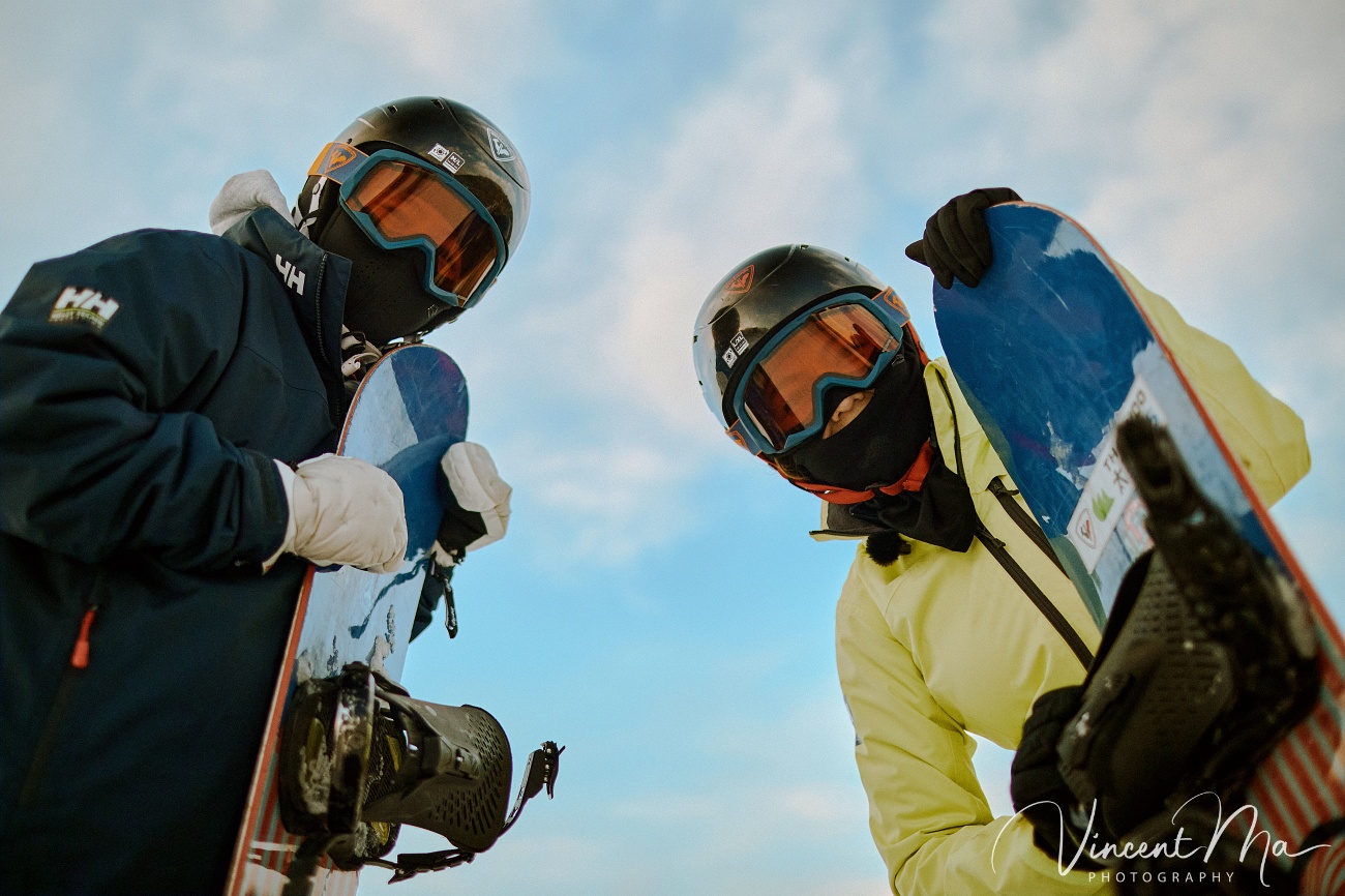 Same-sex couple Claire and April holding hands on a snowy slope in Chongli at a ski resort to celebrate their online wedding.