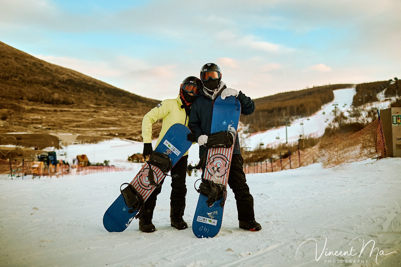 Same-sex couple Claire and April holding hands on a snowy slope in Chongli at a ski resort to celebrate their online wedding.