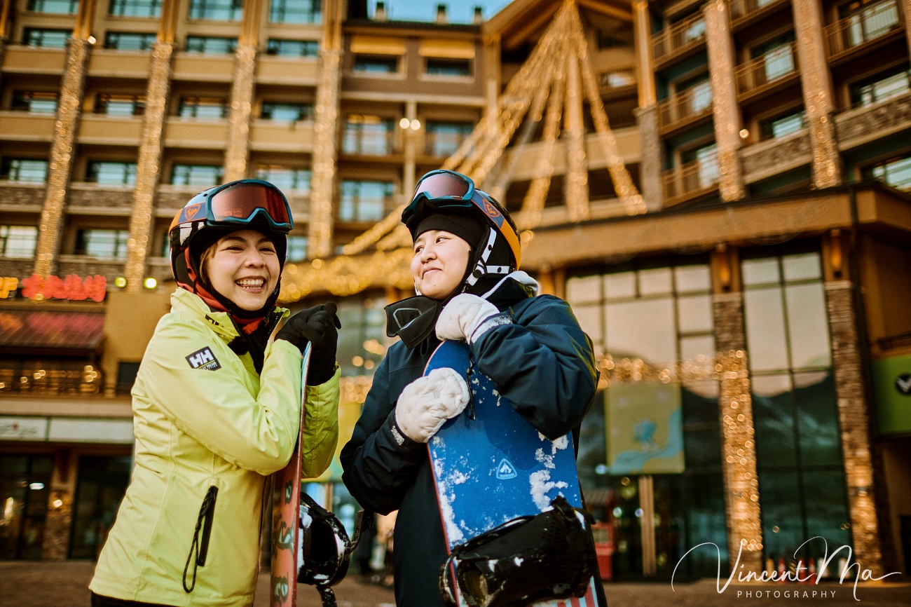 Two brides Claire and April holding hands on a snowy slope in Chongli