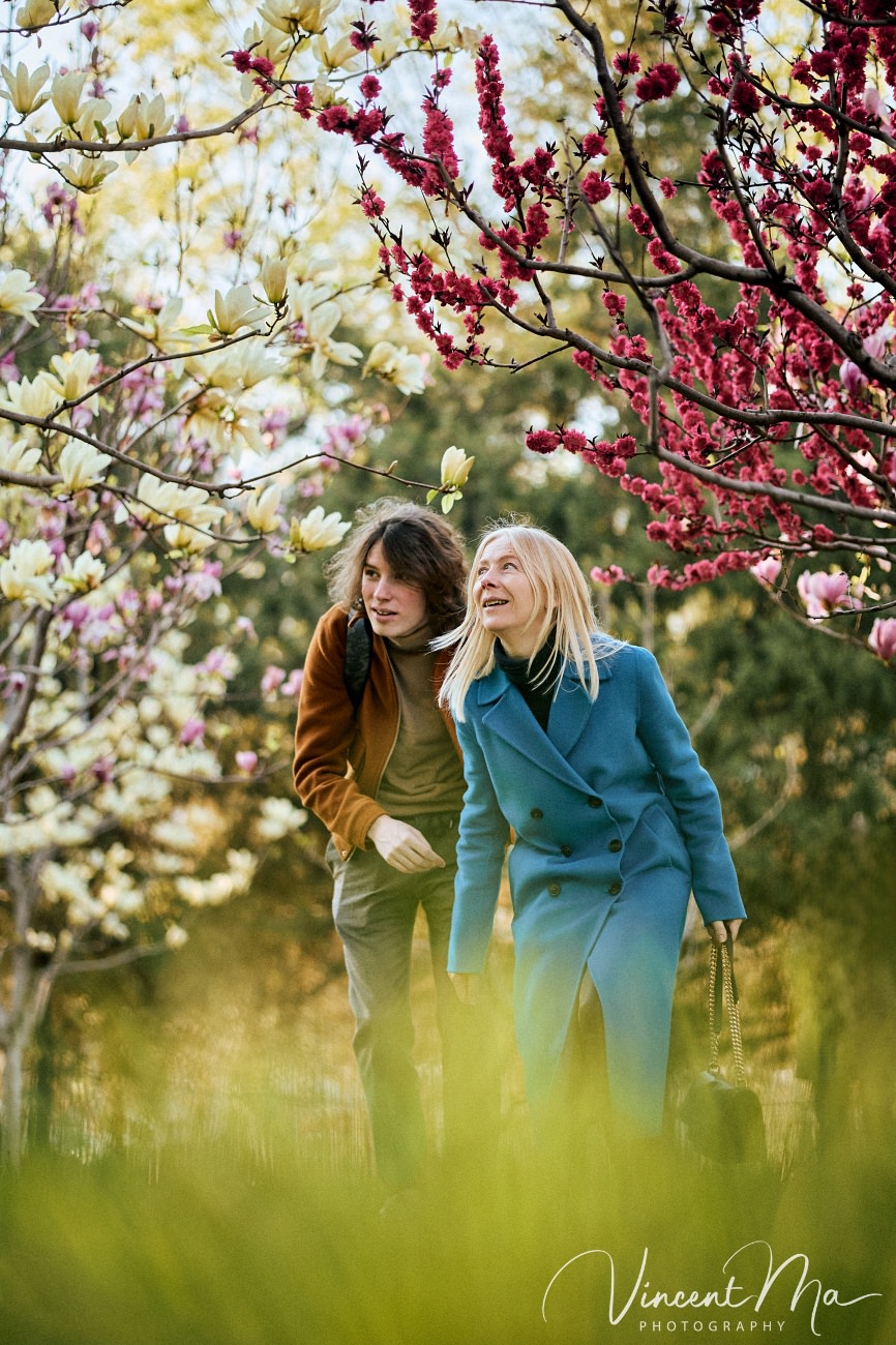 Cinematic portrait of a mother admiring white magnolias in Ritan Park Beijing by Vincent Ma.