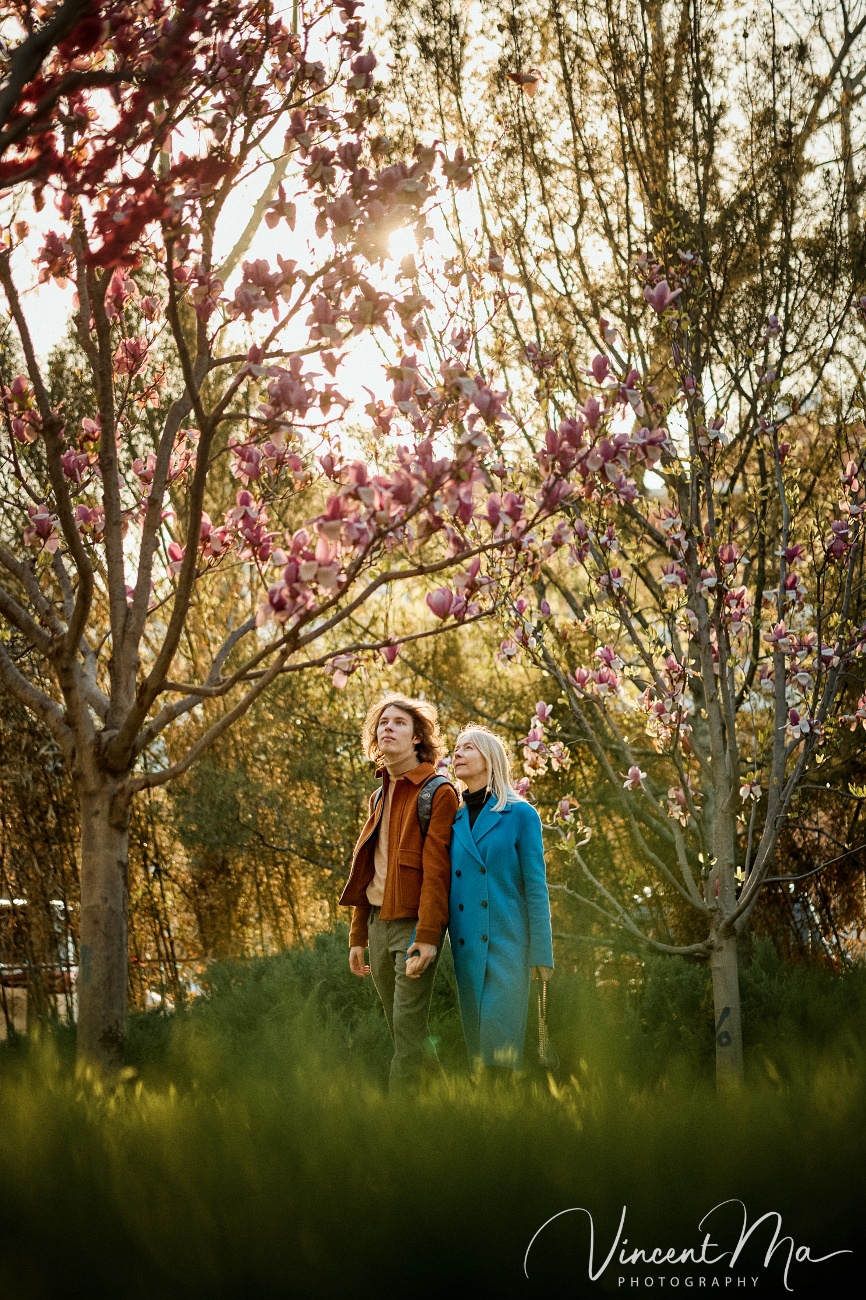 Cinematic portrait of a mother admiring white magnolias in Ritan Park Beijing by Vincent Ma.