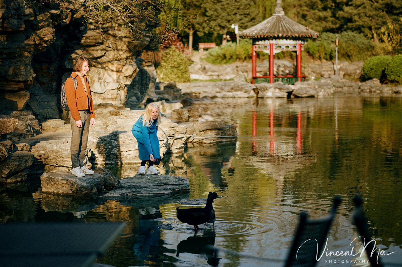 Family travel photography in Beijing featuring traditional red walls and golden hour sunlight.