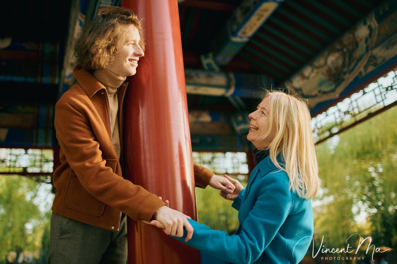 Family travel photography in Beijing featuring traditional red walls and golden hour sunlight.