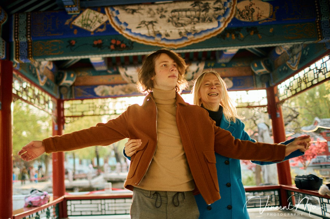 Family travel photography in Beijing featuring traditional red walls and golden hour sunlight.
